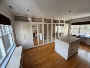 Custom walk-in closet installation featuring mirrored doors and storage wall